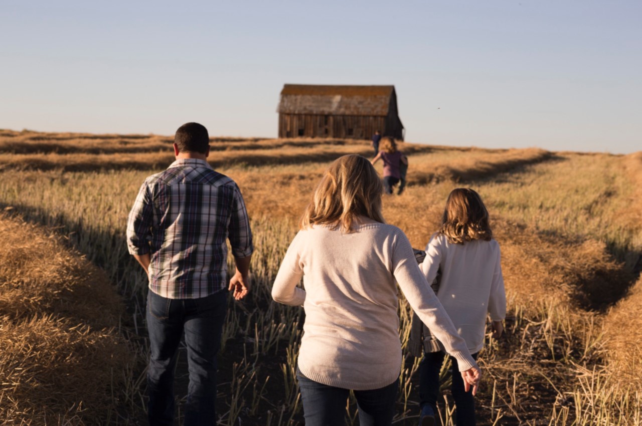 A family walking through a golden field, headed towards an isolated barn - Total and Permanent Disability Insurance