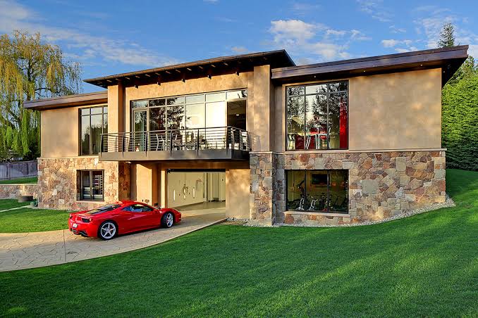 A large house with an expensive sports car on the drive.