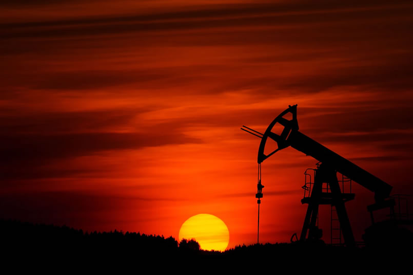 A stunning red sky and setting sun behind the silhouette of oilfield machinery.