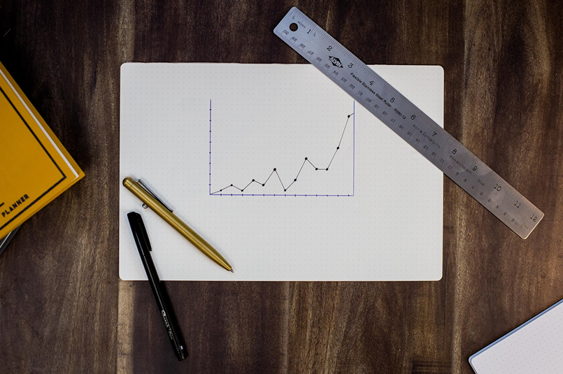 Balanced Investments, or Super Misleading?: A hand-drawn line graph on graph paper, surrounded by stationary on a desk top.