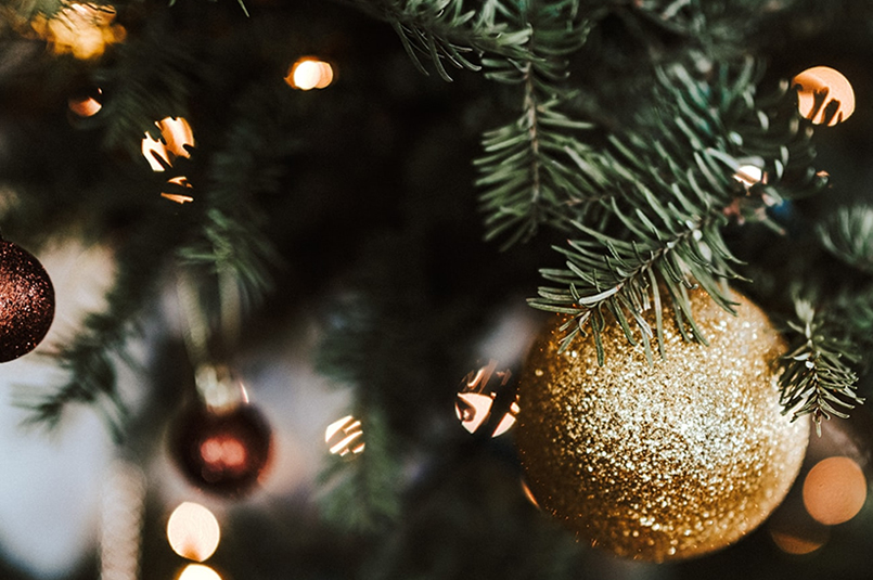 December 2021 Newsletter: Close-up image of lights and golden baubles hanging on a Christmas tree.